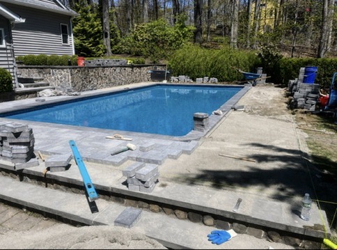 Backyard inground pool with new stone paver surround and coping installed by Liberty Landscaping and Construction.